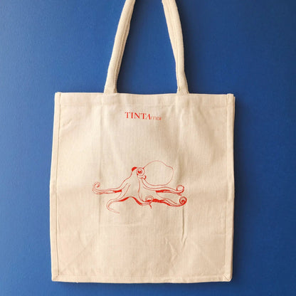 Bolsa de tela TINTAmar color crudo con ilustración de pulpo dibujado a mano sobre fondo azul